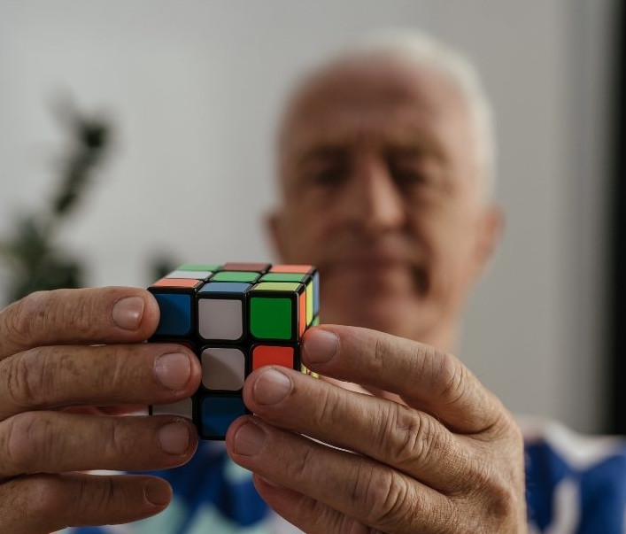 en äldre man löser rubiks kub som sin hjärngympa